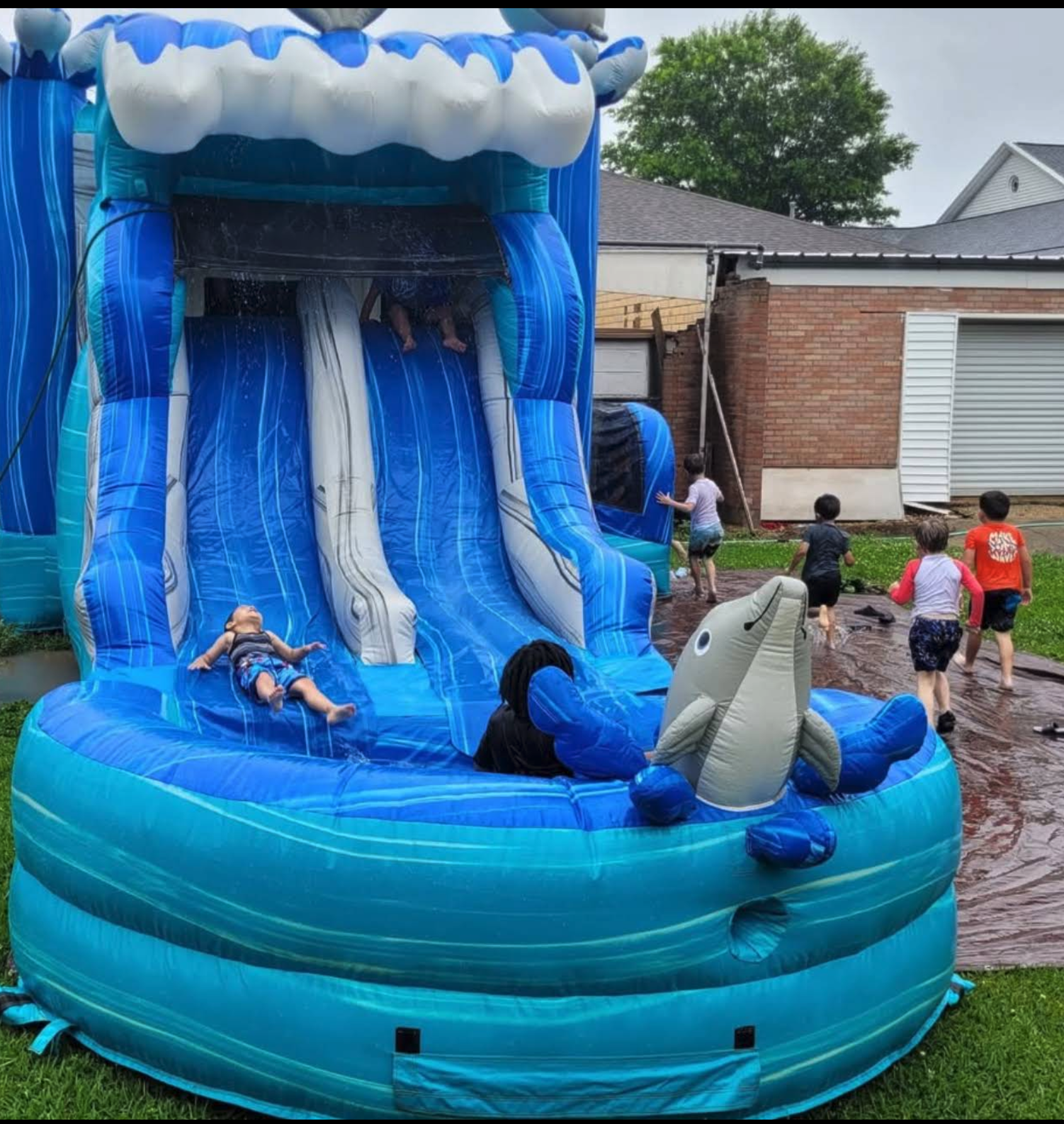 Kids playing on backyard inflatable water slide rental as