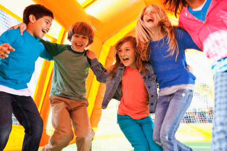 Kids laughing and jumping inside a colorful bounce house