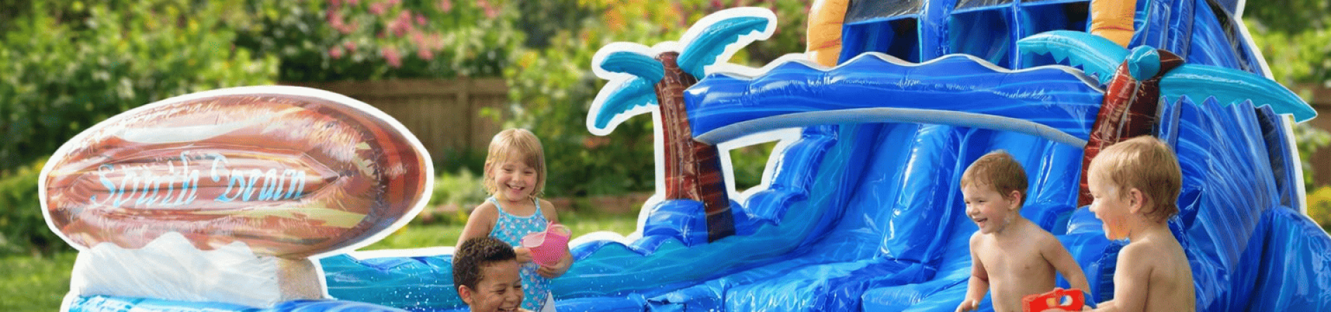 Kids playing on a backyard water slide bounce house in a sunny spring setting