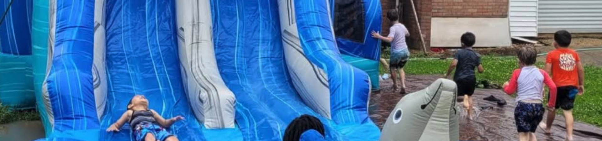 Kids playing on backyard inflatable water slide rental as